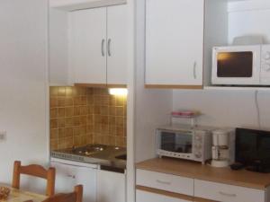 een keuken met witte kasten en een magnetron bij Appartement Mont-Dore, 2 pièces, 4 personnes - FR-1-415-8 in Le Mont-Dore