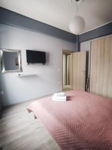 a room with a bed and a tv on the wall at Efrosini's by the sea apartment in Chalkida