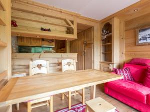 een woonkamer met een houten tafel en een rode bank bij Studio La Clusaz, 1 pièce, 4 personnes - FR-1-437-8 in La Clusaz