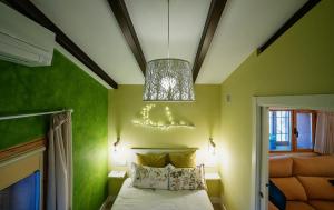 a bedroom with green walls and a bed with a chandelier at Casa Rural Manitoba Luxe in Buenache de la Sierra