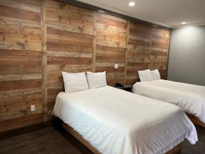 two beds in a room with wooden walls at The Symphony Inn & Suites in Houston