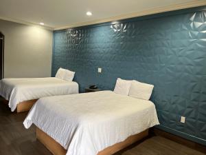 2 Betten in einem Zimmer mit blauer Wand in der Unterkunft The Symphony Inn & Suites in Houston