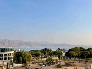 een uitzicht op een strand met een gebouw en bomen bij Sunny 3BR Apartment Golf Residence in Eilat