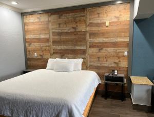 a bedroom with a bed and a wooden wall at The Symphony Inn & Suites in Houston