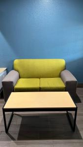 a yellow couch in a room with a table at The Symphony Inn & Suites in Houston