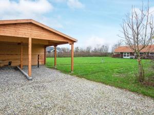 einem Holzpavillon mit einem Grasfeld und einem Haus in der Unterkunft 6 person holiday home in Sydals in Vibøge