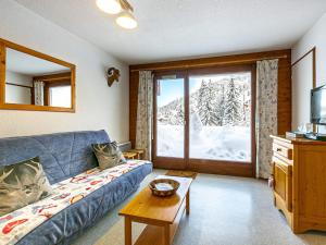 a living room with a blue couch in front of a window at Appartement La Clusaz, 2 pièces, 4 personnes - FR-1-437-78 in La Clusaz