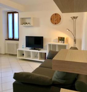sala de estar con sofá, TV y reloj en Casa del borghetto, en Intra