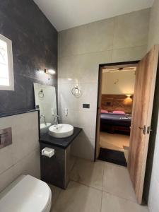 a bathroom with a sink and a toilet and a bedroom at PPH Living Athithi Inn Corporate Stay in Coimbatore +42 photos