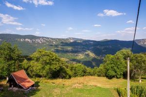 a house on a hill with mountains in the background at Apartmani Rocen in Žabljak