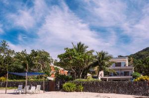 ein Haus am Strand mit Stühlen und einem Sonnenschirm in der Unterkunft Casa Margot - Casas de Luxo Pé na Areia in Juquei