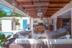 uma sala de estar exterior com sofás e uma mesa em Casa Margot - Casas de Luxo Pé na Areia em Juqueí