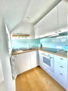 a kitchen with white cabinets and a wooden floor at Loft apartment in Joppa in Edinburgh