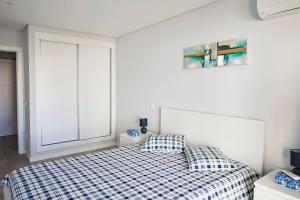 a white bedroom with a bed and a window at Nice apartment near the beach - Monte Gordo in Monte Gordo