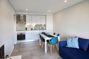 a kitchen with a blue couch and a table and chairs at Nice apartment near the beach - Monte Gordo in Monte Gordo