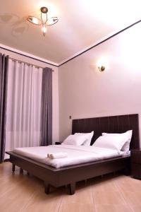 a bedroom with a large bed with white sheets at Hilltop apartments in Bwebajja