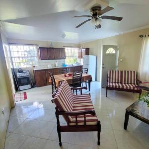 a living room with chairs and a kitchen with a ceiling fan at 1 Bed Apt overlooking Rodney Bay in Gros Islet