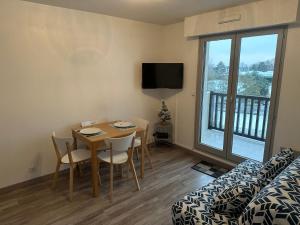 a living room with a table and chairs and a tv at 2 Pieces acces Mer et Thalasso in Cabourg