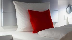 almohada roja sobre una cama blanca en B&b Art Boutique en Mantua