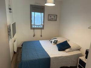 a bedroom with a bed with blue sheets and a window at 2 Pieces acces Mer et Thalasso in Cabourg