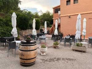 eine Terrasse mit Tischen, Stühlen und weißen Sonnenschirmen in der Unterkunft El Molí de Pontons suites con jacuzzi spa in Pontons