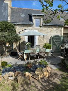 een patio met een tafel en een parasol bij Cosy's Kerguelen - Longère jardin in Larmor-Plage