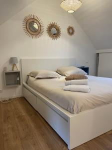 - une chambre avec un lit blanc et 2 miroirs sur le mur dans l'établissement Cosy's Kerguelen - Longère jardin, à Larmor-Plage