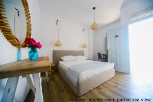 a bedroom with a bed and a vase of flowers on a table at St. Paul's Bay View Suites in Líndos