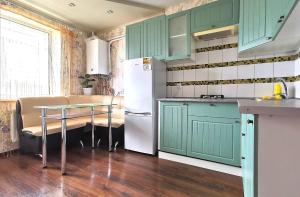 a kitchen with green cabinets and a table and a refrigerator at Lavina apartments in Sumy