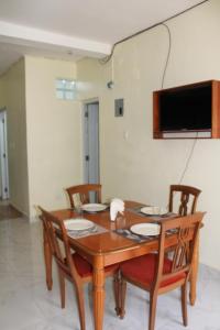 a wooden table with chairs and a television on a wall at Apartamentos VBERMOR in Santo Domingo