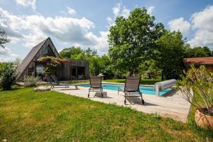 a backyard with a pool and two chairs and a house at Les Trigones du Causse -Maison atypique avec Piscine Privée in Saint-Martin-Labouval