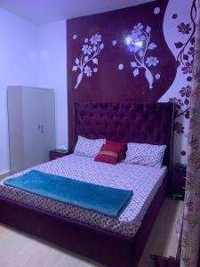 sypialnia z dużym łóżkiem i fioletową ścianą w obiekcie Jacetnouche w mieście Dakar