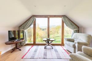 ein Wohnzimmer mit einem Sofa und einem großen Fenster in der Unterkunft Delightful Country Cottage in a lovely rural area in Ludlow