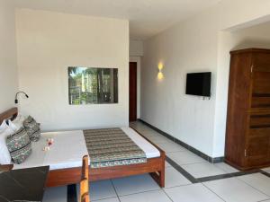 a bedroom with a bed and a tv on a wall at Hôtel Grand Bay in Nosy Be