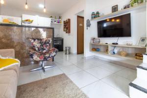 a living room with a chair and a television at Incrível casa na praia de Camurupim por Carpediem in Nísia Floresta +36 photos