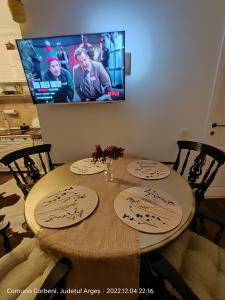 a dining room table with a tv on the wall at Casuta Nest in Curtea de Argeş