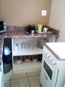 a kitchen with a counter with dishes and a stove at Bisho Park guesthouse in King Williamʼs Town