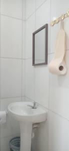 a white bathroom with a sink and a mirror at Pousada Ribeirinha in Aparecida