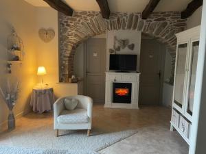 a living room with a fireplace and a chair at Le couvent de Jouels in Sauveterre-de-Rouergue