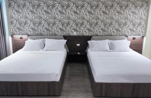 dwa łóżka siedzące obok siebie w pokoju w obiekcie Eslait Hotel & Apartamentos w mieście Barranquilla