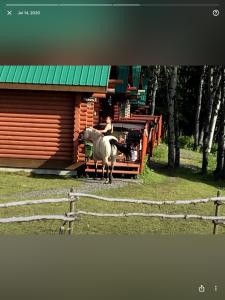 una persona montando un caballo fuera de un edificio en Montana Hill Guest Ranch en Bridge Lake