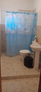 a bathroom with a toilet and a sink with a blue shower curtain at HOSTAL LUPITA in Iruya