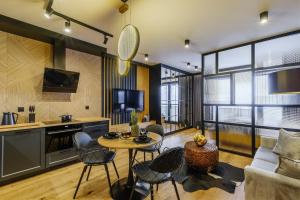 sala de estar con mesa, sillas y sofá en APARTAMENT CHICAGO - stylowy apartament o bardzo wysokim standardzie w centrum miasta, z prywatnym zadaszonym parkingiem - IZBY PODHALAŃSKIE, en Nowy Targ