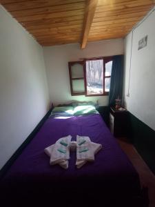 Un dormitorio con una cama morada con toallas. en HOSTAL LUPITA en Iruya