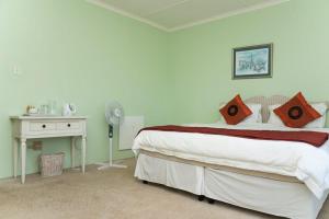 a white bedroom with a bed and a desk and a bed sidx sidx at Bisho Park guesthouse in King Williamʼs Town