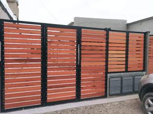 una recinzione con pannelli in legno arancione e marrone di Alquileres Oeste 1 a Puerto Madryn