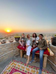 a group of people sitting on a bench watching the sunset at Saffron Homestay in Jaisalmer