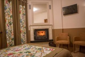 - une chambre avec une cheminée, un lit et deux chaises dans l'établissement Mελίμνια, à Koutsodímos