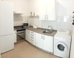 uma cozinha branca com um lavatório e uma máquina de lavar roupa em Casa Analiz em Arrecife