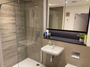 a bathroom with a sink and a shower at Exquisite & Contemporary 2 Bed Apartment w Parking 10 mins walk to Papworth, Addenbrookes hospitals & Bio Medical Campus in Trumpington +29 photos